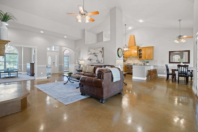 living area featuring arched walkways, recessed lighting, a ceiling fan, high vaulted ceiling, and concrete flooring