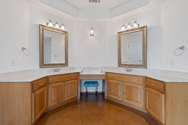 full bathroom featuring a raised ceiling, double vanity, and a sink