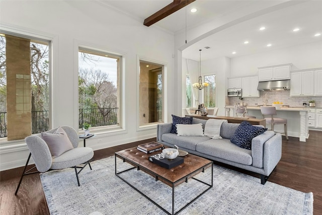 living area with dark wood-style floors, baseboards, arched walkways, and an inviting chandelier