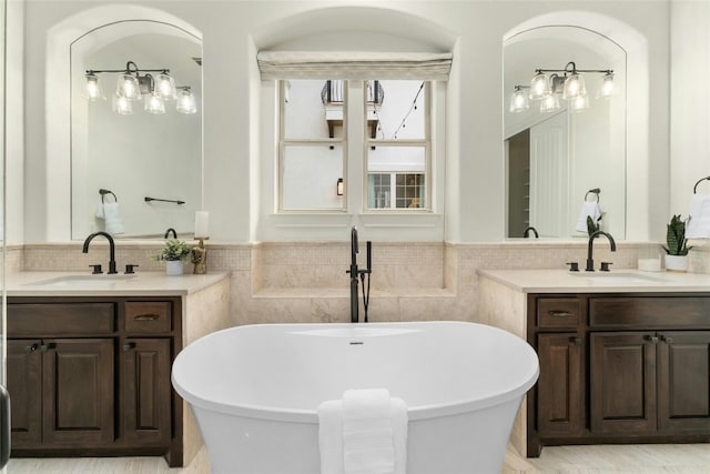 bathroom featuring a wainscoted wall, a freestanding bath, and a sink