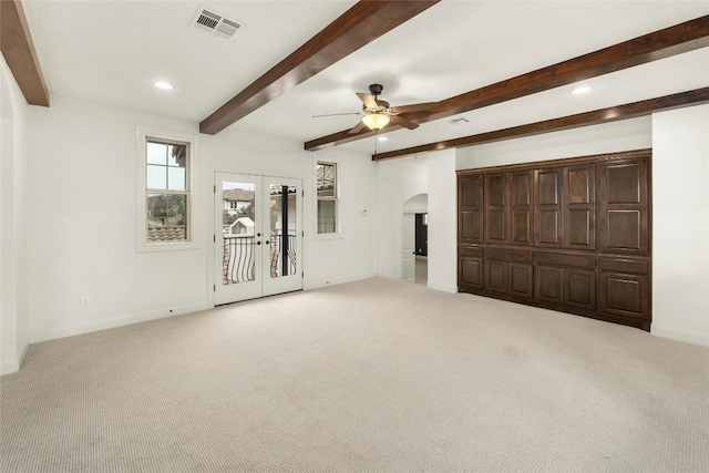 unfurnished bedroom featuring arched walkways, visible vents, and carpet