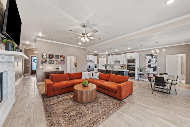 living area with ceiling fan with notable chandelier, light wood finished floors, a fireplace, and visible vents