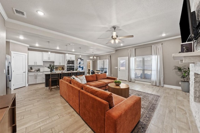 living area featuring a fireplace, visible vents, a textured ceiling, light wood-type flooring, and ceiling fan with notable chandelier