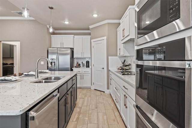 7701 Soapstone Ct, Temple, TX 76502 - kitchen featuring appliances with stainless steel finishes, ornamental molding, white cabinets, backsplash, and hanging light fixtures