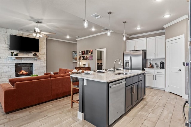 kitchen featuring a fireplace, visible vents, appliances with stainless steel finishes, open floor plan, and white cabinets