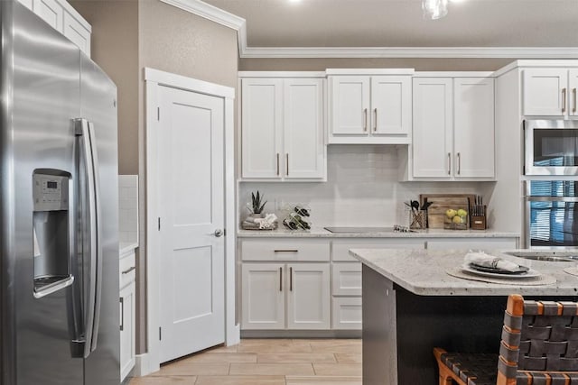 7701 Soapstone Ct, Temple, TX 76502 - kitchen with stainless steel appliances, crown molding, white cabinetry, wood finish floors, and light stone countertops
