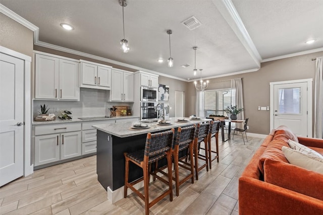 7701 Soapstone Ct, Temple, TX 76502 - kitchen with stainless steel appliances, ornamental molding, wood finish floors, a breakfast bar, and a center island with sink