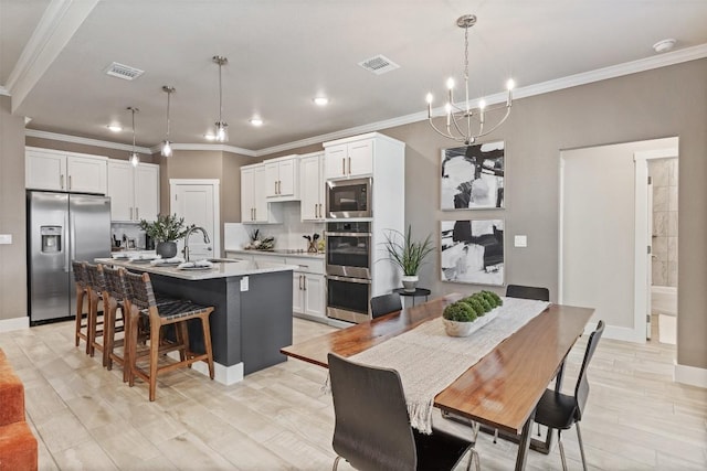 kitchen with a center island with sink, visible vents, stainless steel appliances, and a sink