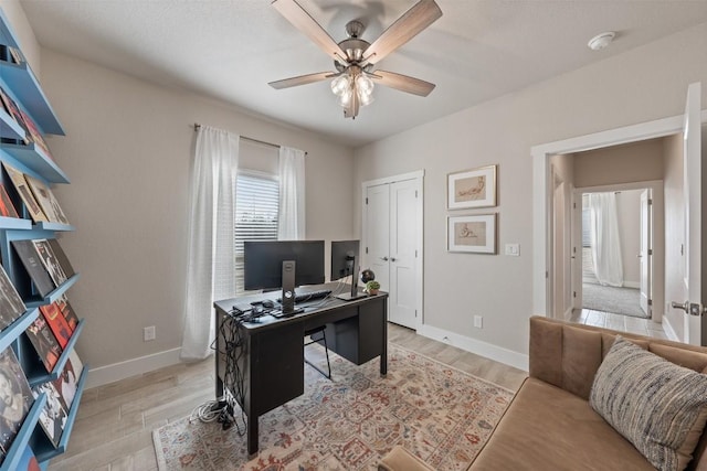 home office featuring a ceiling fan, light wood-type flooring, and baseboards