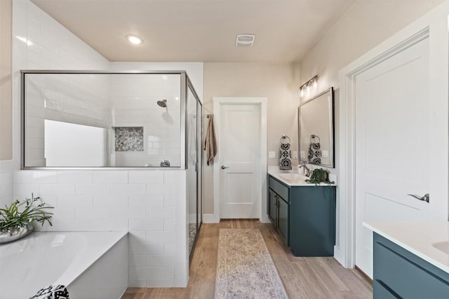 full bathroom featuring a shower stall, a bathtub, wood finished floors, and vanity