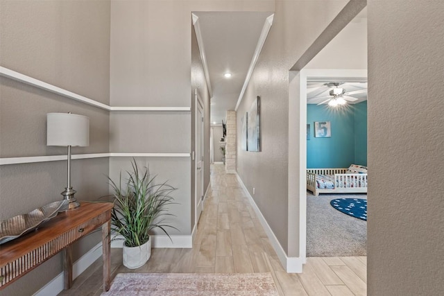 corridor with a textured wall, baseboards, and wood finish floors