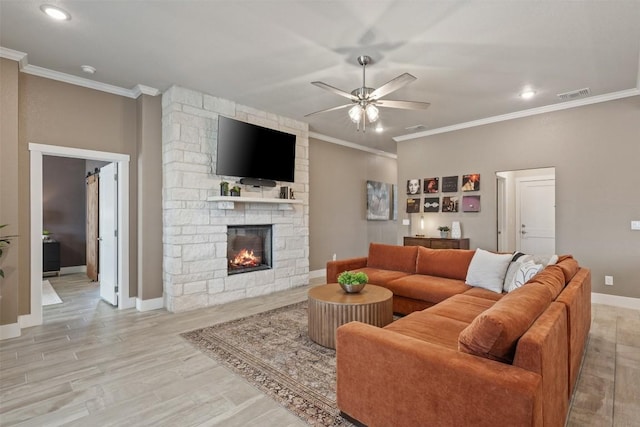 living area featuring a ceiling fan, a fireplace, visible vents, and crown molding