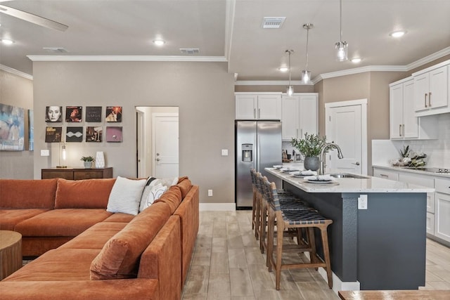 kitchen with a breakfast bar, a sink, open floor plan, stainless steel refrigerator with ice dispenser, and tasteful backsplash