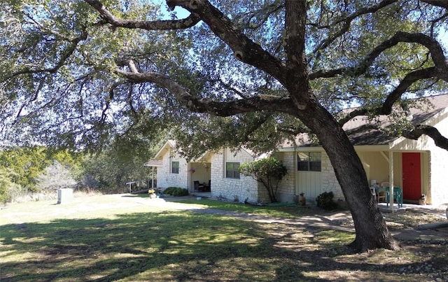 view of front of home featuring stone siding and a front lawn