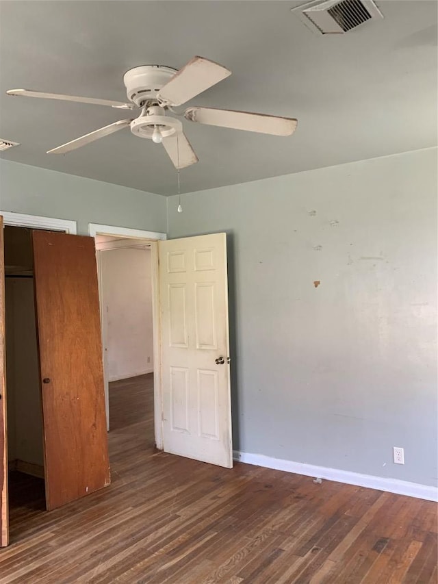 unfurnished bedroom featuring a ceiling fan, visible vents, baseboards, and wood finished floors