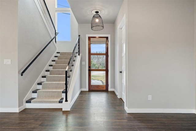 foyer featuring dark wood-type flooring, stairway, and baseboards