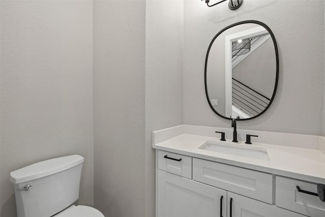 bathroom featuring a textured wall, vanity, and toilet