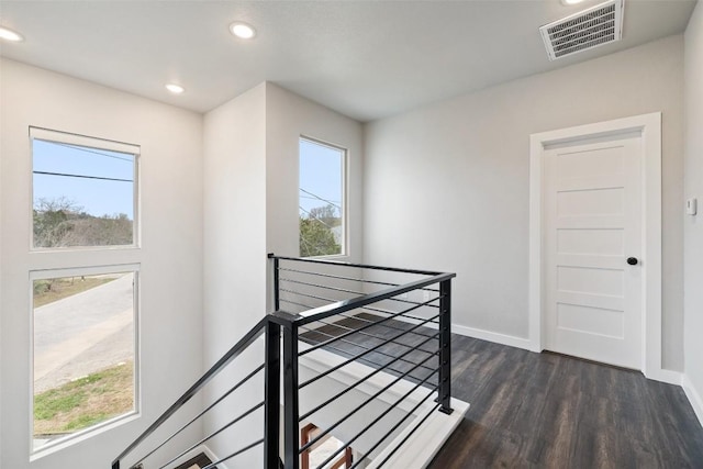 hall featuring dark wood finished floors, an upstairs landing, visible vents, and baseboards