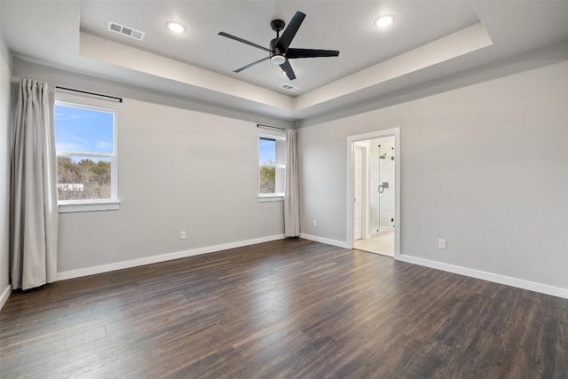 empty room with a raised ceiling, visible vents, and wood finished floors