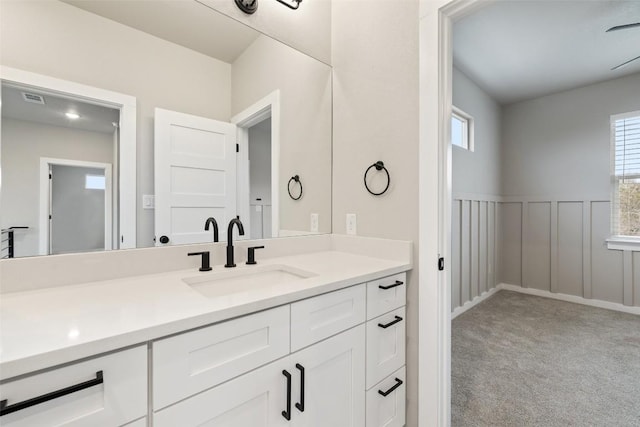 bathroom with a wainscoted wall, visible vents, a decorative wall, and vanity