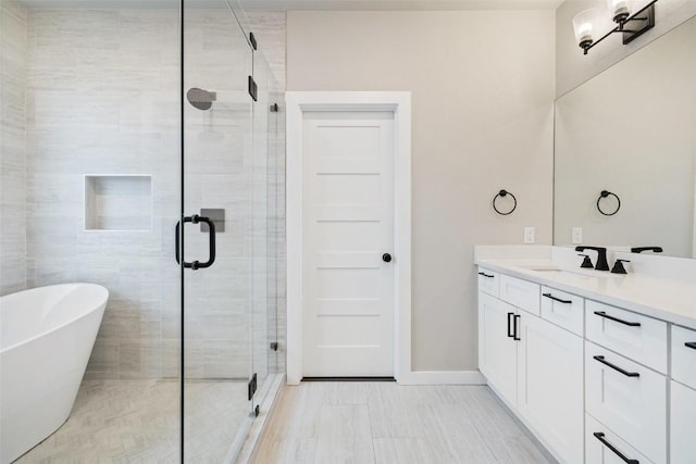 bathroom featuring a stall shower, baseboards, a freestanding tub, and vanity