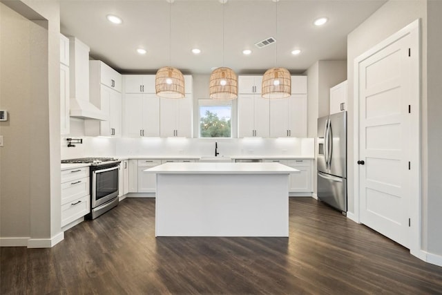 18200 Fair Ln, Jonestown, TX 78645 - kitchen with appliances with stainless steel finishes, a sink, dark wood finished floors, light countertops, and a center island