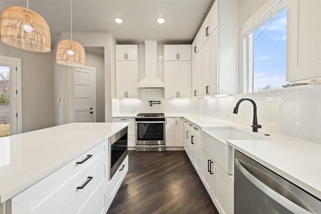 kitchen with decorative backsplash, dark wood-style floors, appliances with stainless steel finishes, light countertops, and wall chimney range hood