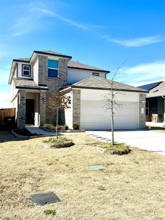 prairie-style home featuring a garage, concrete driveway, and brick siding