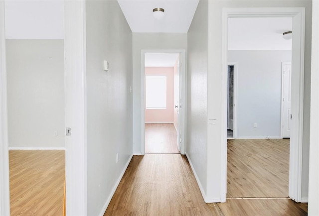 hall featuring light wood-type flooring and baseboards