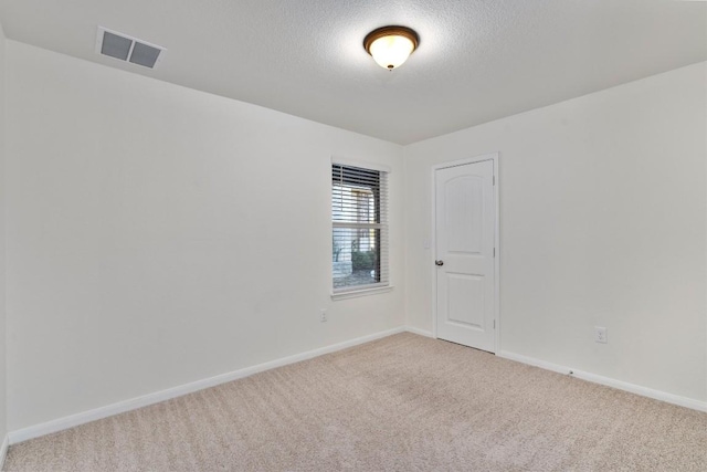 unfurnished room with visible vents, light carpet, baseboards, and a textured ceiling