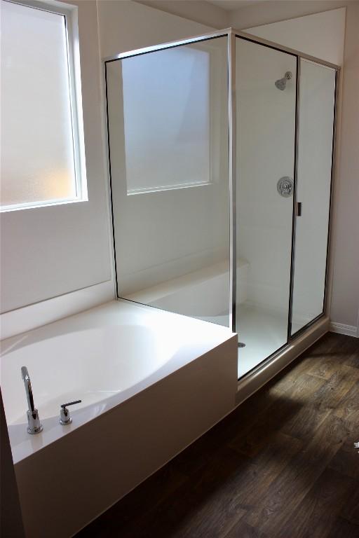 full bathroom featuring a garden tub, a shower stall, and wood finished floors