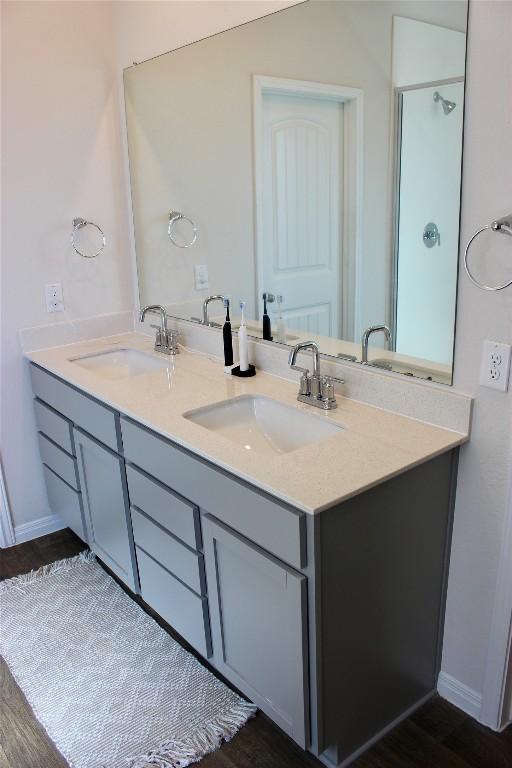 full bathroom featuring double vanity, a sink, and baseboards