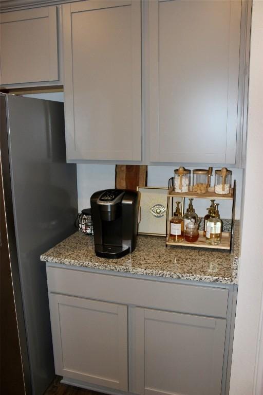 kitchen with light stone counters, gray cabinets, and freestanding refrigerator