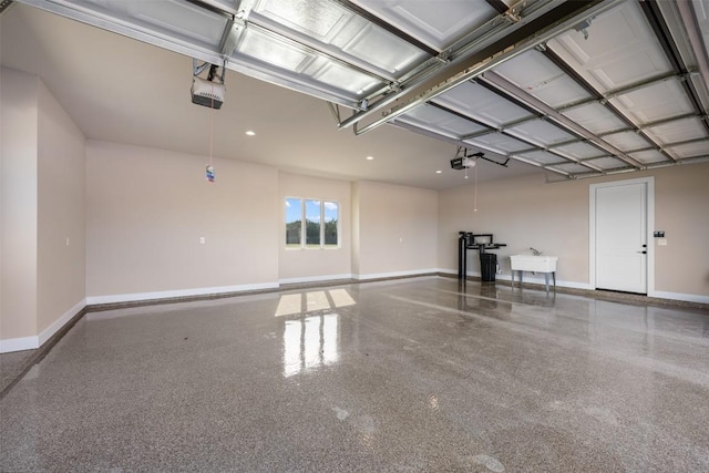 garage with a garage door opener, a sink, and baseboards