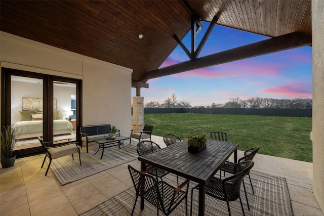 patio terrace at dusk featuring an outdoor living space, a lawn, and outdoor dining space