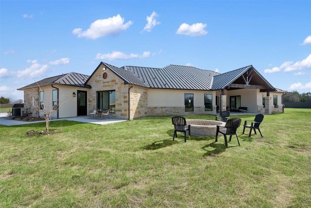 back of house featuring a yard, an outdoor fire pit, a standing seam roof, a patio area, and metal roof