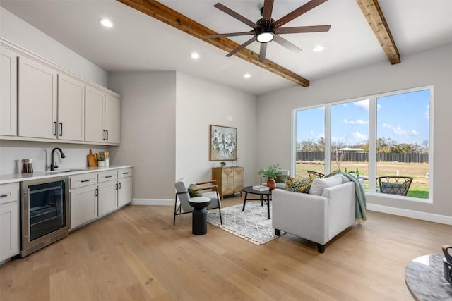 interior space with wine cooler, beamed ceiling, light wood-style flooring, and baseboards