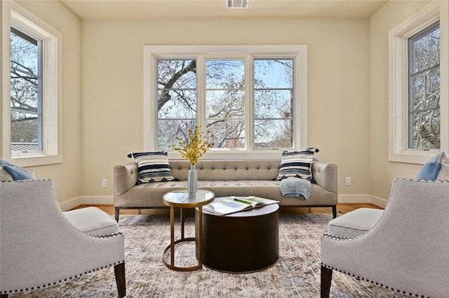 living area with baseboards, a wealth of natural light, and wood finished floors