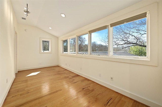 empty room featuring lofted ceiling, visible vents, plenty of natural light, and light wood-style flooring