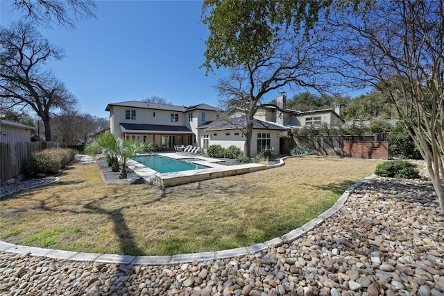 back of house featuring a fenced backyard, a fenced in pool, a lawn, and a patio