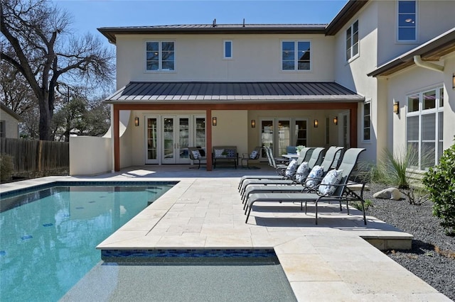 rear view of property with fence, french doors, stucco siding, a standing seam roof, and a patio area