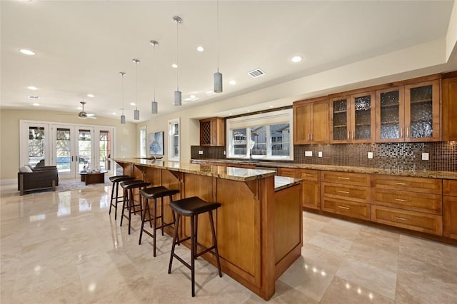 kitchen with french doors, backsplash, glass insert cabinets, and brown cabinets