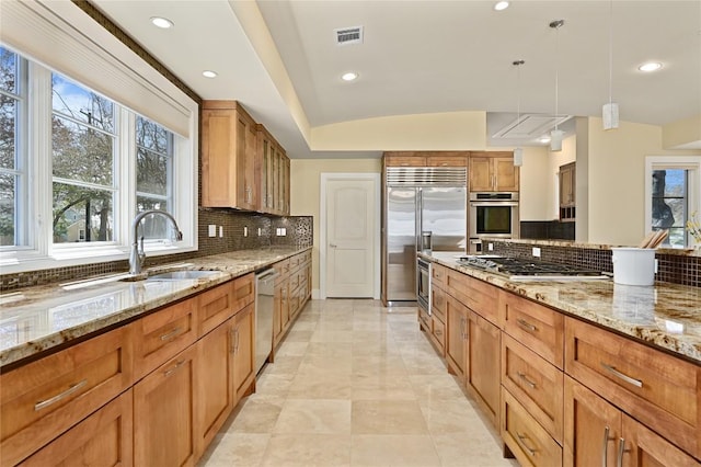 kitchen with stainless steel appliances, plenty of natural light, and light stone counters