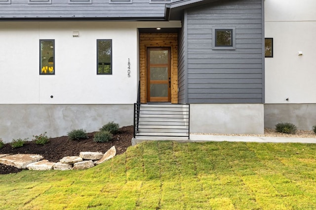 doorway to property with a lawn and stucco siding