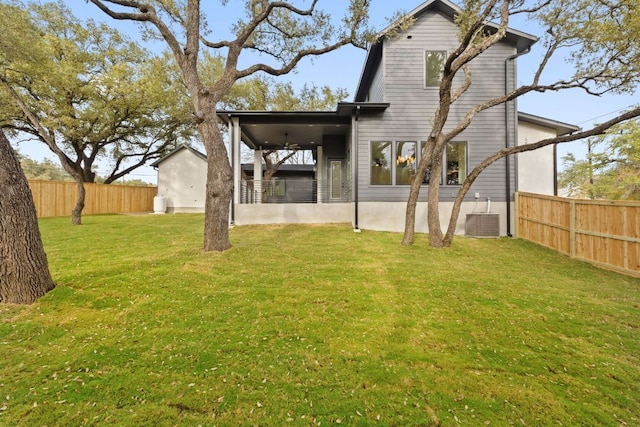 rear view of property featuring a yard, cooling unit, and fence private yard