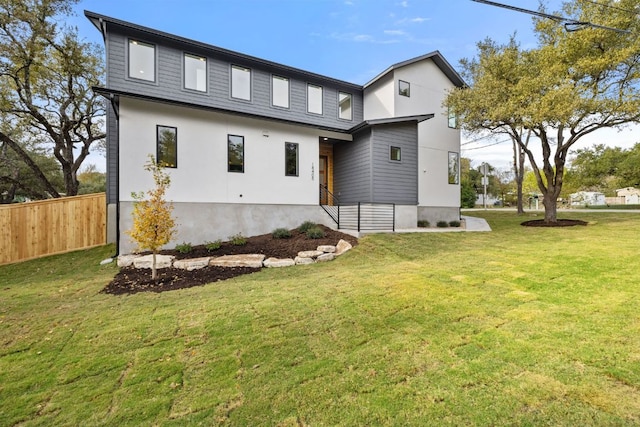 rear view of house featuring a lawn and fence