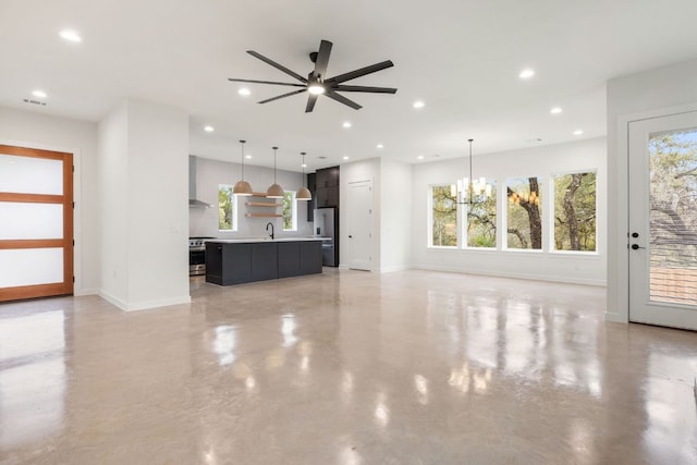 unfurnished living room with recessed lighting, visible vents, baseboards, a sink, and ceiling fan with notable chandelier