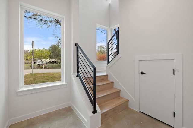 stairs featuring finished concrete floors and baseboards