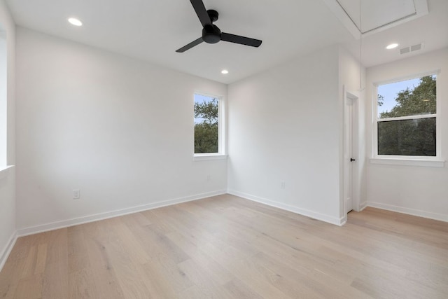 empty room with attic access, baseboards, visible vents, and light wood finished floors