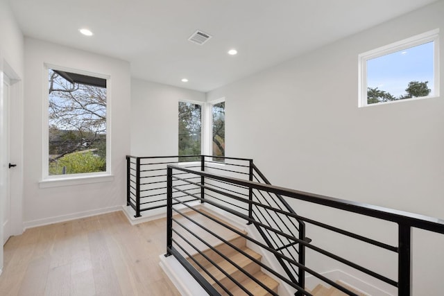 corridor featuring recessed lighting, light wood-style flooring, visible vents, and an upstairs landing